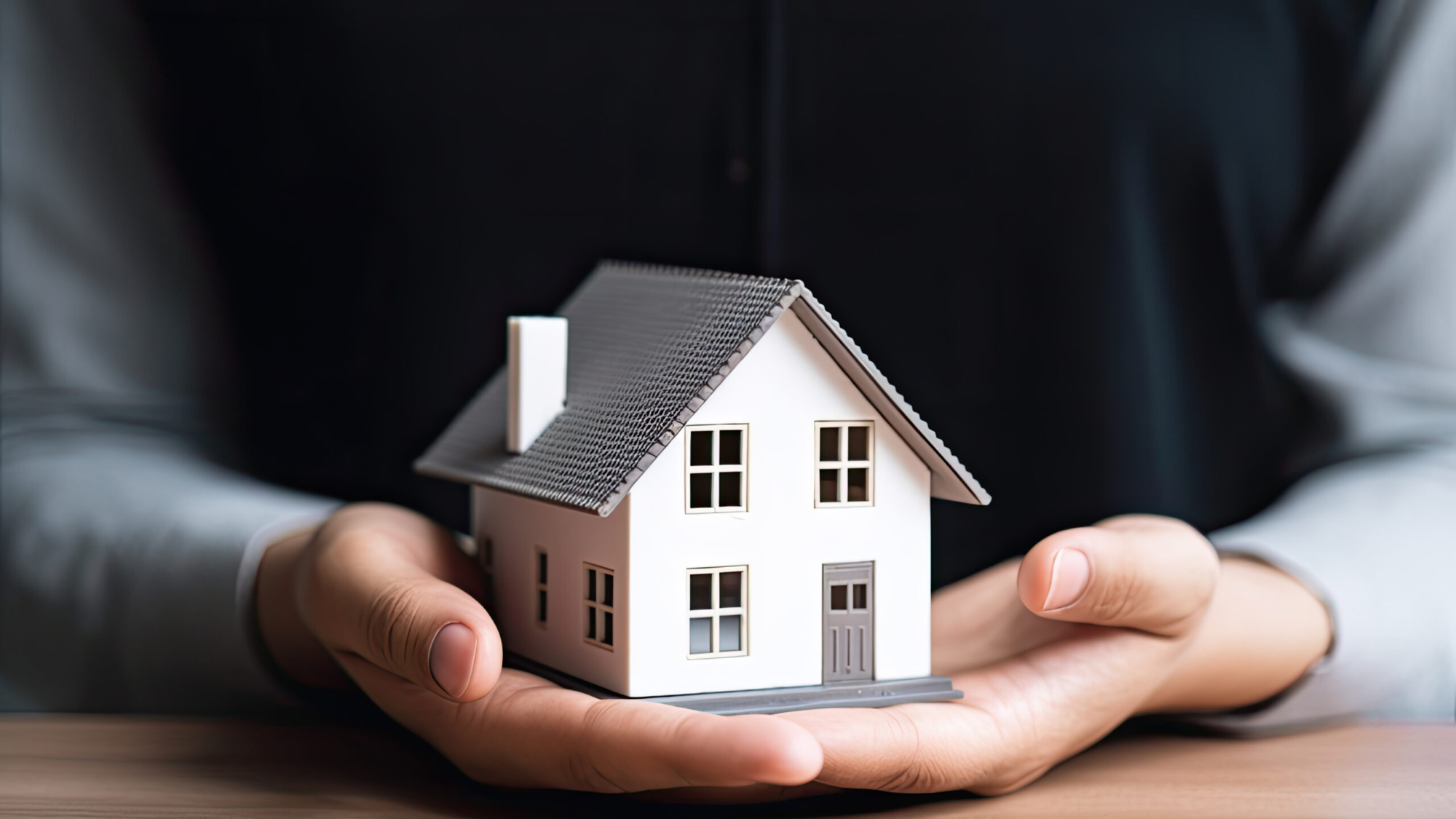 woman showing with one hand a mini house. Real state concept.